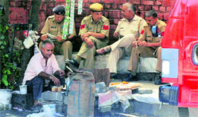 Police personnel wait for their cup of tea at a roadside vend in Gurgaon.