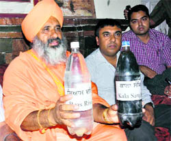 Punjab Pollution Control Board member Sant Balbir Singh Seechewal shows polluted waters of the Beas and Kala Sangha drain, collected in bottles, to mediapersons in Patiala on Sunday.