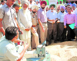 Darbara Singh Guru, Principal Secretary to the Punjab Chief Minister, gets the moisture content of paddy checked during a visit to the grain market in Bathinda 