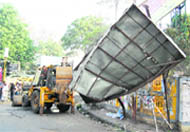 A hoarding being removed by the municipal staff in Dehradun. 