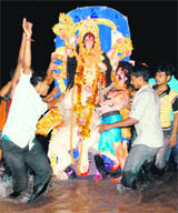 ; and (right) devotees immerse an idol of Goddess Durga in Ghaggar river, 
