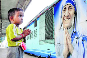A child prays in front of a portrait of Mother Teresa as an express train arrives at Moradabad railway station on Monday.