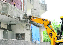 A JCB machine demolishes illegal structures at Mani Majra on Thursday