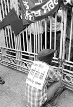 A member of the Unemployed Lineman Union, Punjab, locks the gate of Punjab State Power Corporation Limited office during a protest in Patiala on Thursday