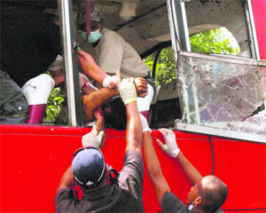 Rescuers pull out the body of one of the victims of a bus explosion in Matalam, Philippines, on Thursday. Nine persons were killed in the attack.