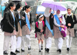 Schoolgirls walk with umbrellas in the rain in Srinagar on Friday