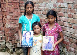 The three sisters with photos of their parents who died of AIDS.