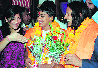 Geeta and Babita, sisters from Haryana who won gold and silver, respectively, in wrestling during the Commonwealth Games, being welcomed in Mohali on Sunday.