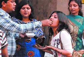 A woman, with henna applied on her hands, is helped by her husband in savouring a golgappa at Dhobi Bazaar
