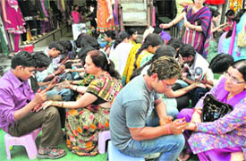 Women get henna applied on their hands.