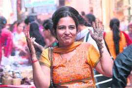 A woman in a joyous mood shows her hands with mehndi applied on them.