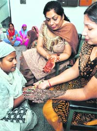 Jail superintendent Snehjot (middle) shows her heena-applied palms, while another prison official gets the same applied on her hands by a jail inmate