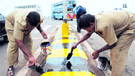 Workers of the BMC paint a road divider ahead of US President Barack Obamas visit, in Mumbai on Monday.