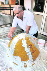 A sweet-maker decorates a 64-kg ladoo with dry fruits. 
