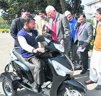 Governor NN Vohra presents a scooter to a representative of the All J&K Handicapped Association in Srinagar.