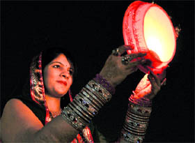 A woman looks at the moon through a sieve before breaking her fast on the occasion of Karva Chauth in Ludhiana on Tuesday.