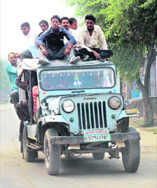 A jeep overloaded with passengers plies on the Sunarian-Rohtak road. 