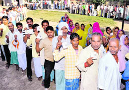 Voters display their identity cards as they wait to cast their votes during the third phase of the Bihar Assembly elections in Raghopur on Thursday