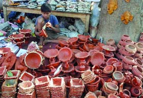 A boy paints a diya ahead of Divali near Sarojini Nagar Market in New Delhi
