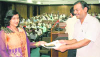 Maneesha Bansal Badal, Director, Postal Services, Haryana circle, Ambala, honours a postal employee during a rural postal insurance fair at Kurukshetra.