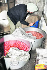 A health official inspects sweets at a shop on the Gill road in Ludhiana on Monday.