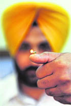 Artist Harwinder Singh Gill presents a miniature diya balanced on his thumb in Amritsar on Thursday.