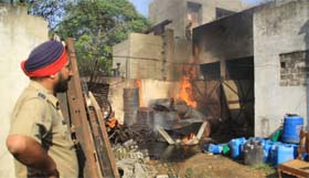 A policeman watches as fire rages on in the Baradari police station