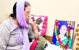 A pensive Rajeshwari Mattoo, mother of Priyadarshini Mattoo, looks at the garlanded photo of her deceased daughter at her house in Patel Nagar in Jammu.