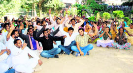 Members of the Fourth Class Employees Association of the Municipal Corporation hold a dharna outside the corporation office in Jammu on Saturday.