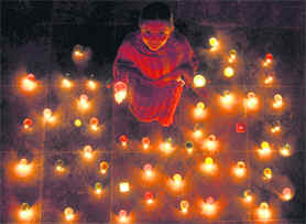 A girl sits amidst lit earthen lamps during the festival of lights in Ludhiana on Friday.