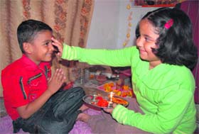 A girl applies tilak on the forehead of her brother in Dehradun
