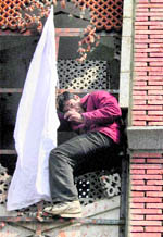 A protesting youth hoists a white flag at Clock Tower in Srinagar on Sunday