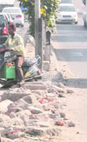Commuter crosses a road divider on the busy Ferozepur Road, which requires immediate repairs