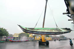 A fishing boat is moved from the shore to the side of a road during heavy rain in Chennai on Sunday.