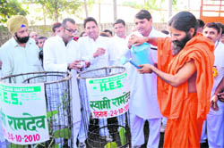 Swami Ramdev waters saplings aided by Dr S.L. Saini, president, Haryana Environmental Society, at Yamunanagar. 