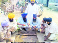 An Agricultural Development Officer, Dr Jaswinder Singh Brar, (third from left) demonstrates the technique of germination test of wheat seeds in Moga village