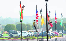 Workers remove the US and Indian flags after the departure of US President Barack Obama in New Delhi