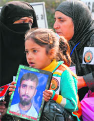 Tabia Shreef holds a picture of her missing relative, Showkat Ahmad Paul of Rawalpora, at a demonstration in Srinagar on Wednesday. 