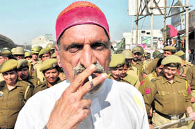 With cops standing behind him, a BJP worker smokes in the public in Jammu on Thursday.