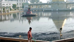 A devotee at Devi Talab Mandir cleans the ash emanated from the chimneys of industrial units in Jalandhar.