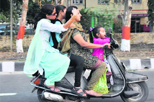Three women and a child ride a scooter in violation of traffic rules in Jammu.