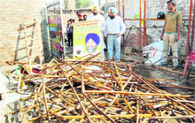 MLA Manjinder Singh Kang shows damaged hoardings carrying Manpreet Badals picture in Amritsar on Saturday.