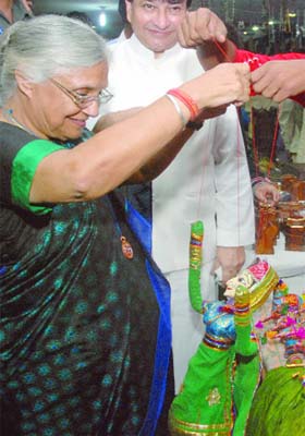 Delhi Chief Minister Sheila Dikshit plays with a puppet after opening the event