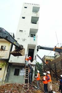 MCD labourers work at a tilted four-storey building at Mahavir Enclave in New Delhi