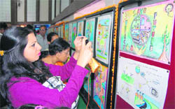 Visitors look at paintings made by children at a painting competition in Dehradun on Sunday. 