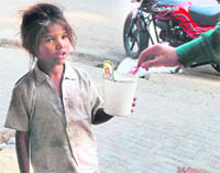 A child, in tattered clothes, begs for alms at a roadside in Jammu on Sunday