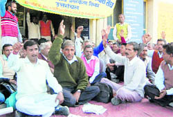Members of the Rajya Karamchari Sangh stage a dharna in Dehradun on Monday.