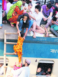 A man helps a child climb on to the roof of an overcrowded train at a railway station in Dhaka on Monday. Millions of residents in Dhaka are travelling home from the capital city to celebrate Eid al-Adha on Wednesday.