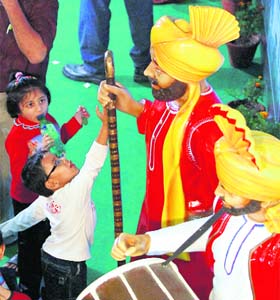 Children play with statues of bhangra dancers at the Punjab pavilion during the India International Trade Fair at Pragati Maidan in New Delhi