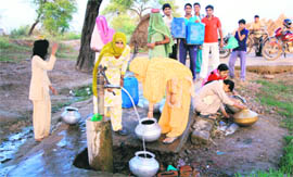 Residents of Sundana village collect water from a hand pump.